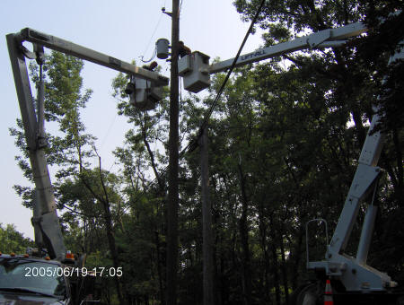 Photo of power company workers installing transformer on pole